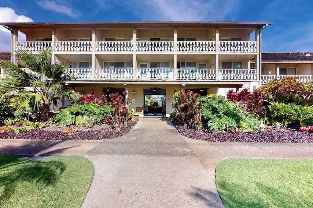 Un hotel de varios pisos con una entrada central, balcones en cada planta y jardines bien cuidados.