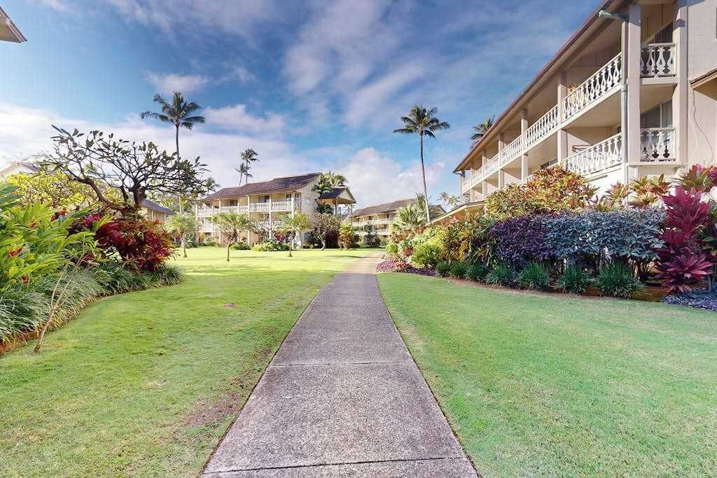 A hotel with a central pathway, palm trees, and a building with balconies.