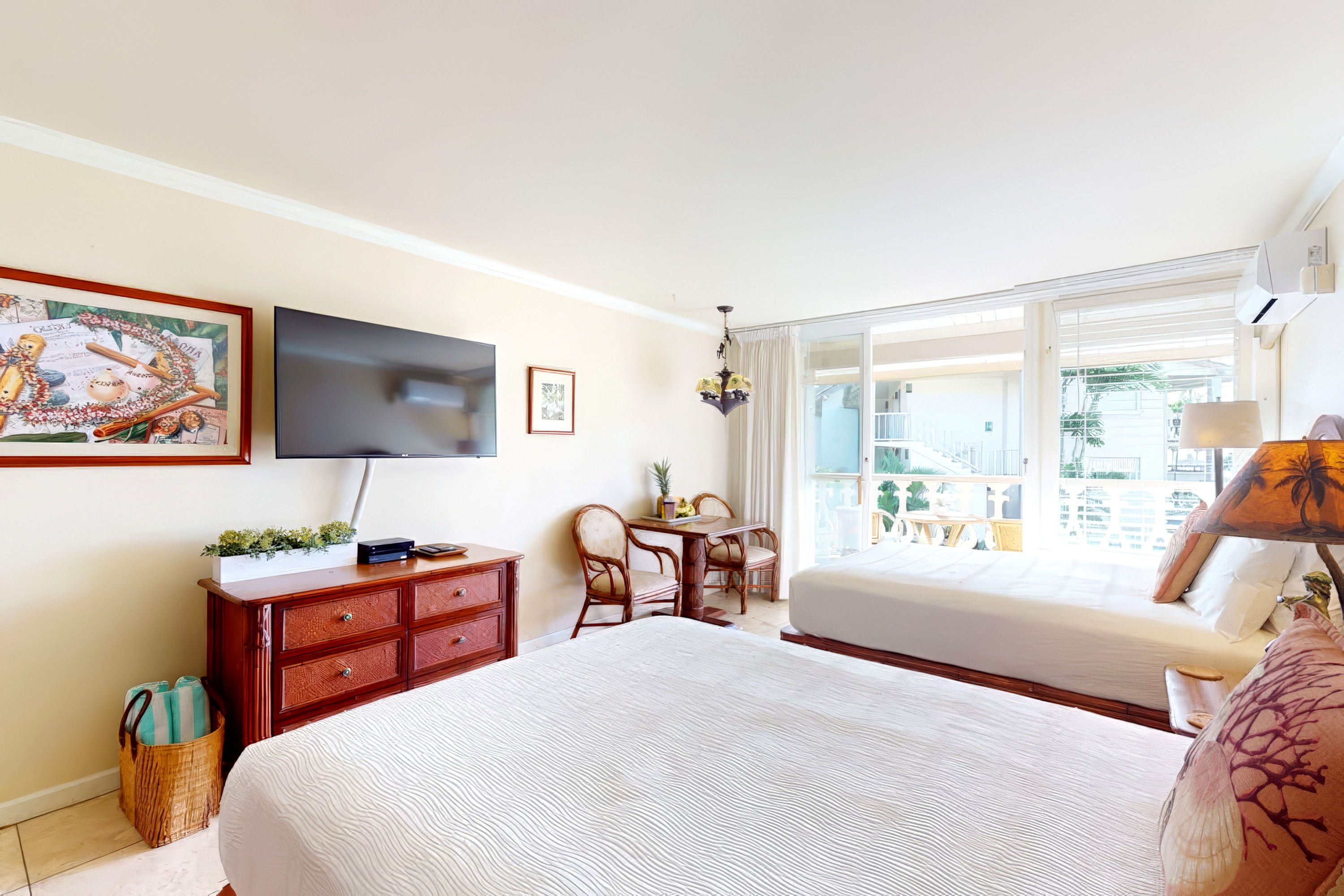 A hotel room with a large bed, a flat-screen TV mounted on the wall, a desk with a chair, and a window with a view of the outside.