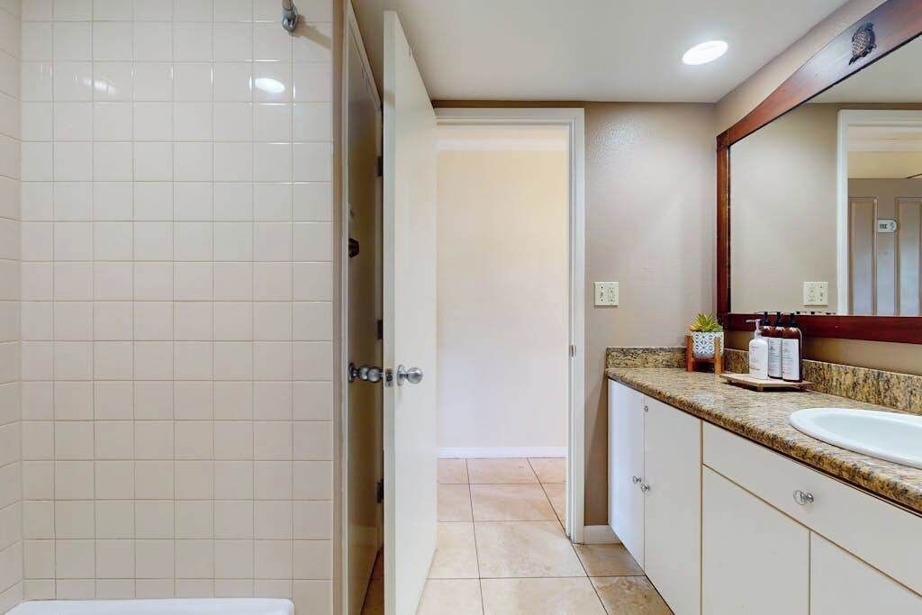 Un bany amb un lavabo blanc, un mirall i una porta de banyera.