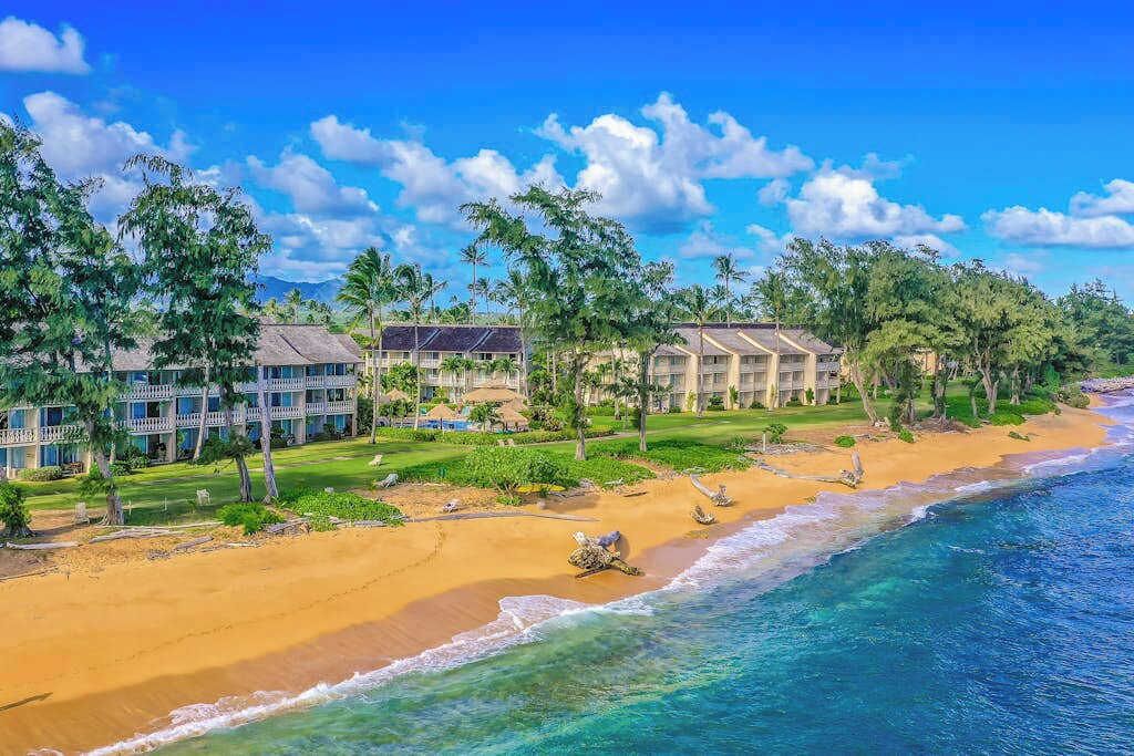 Ein Hotel direkt am Strand mit mehreren Gebäuden, einem Sandstrand und Palmen.
