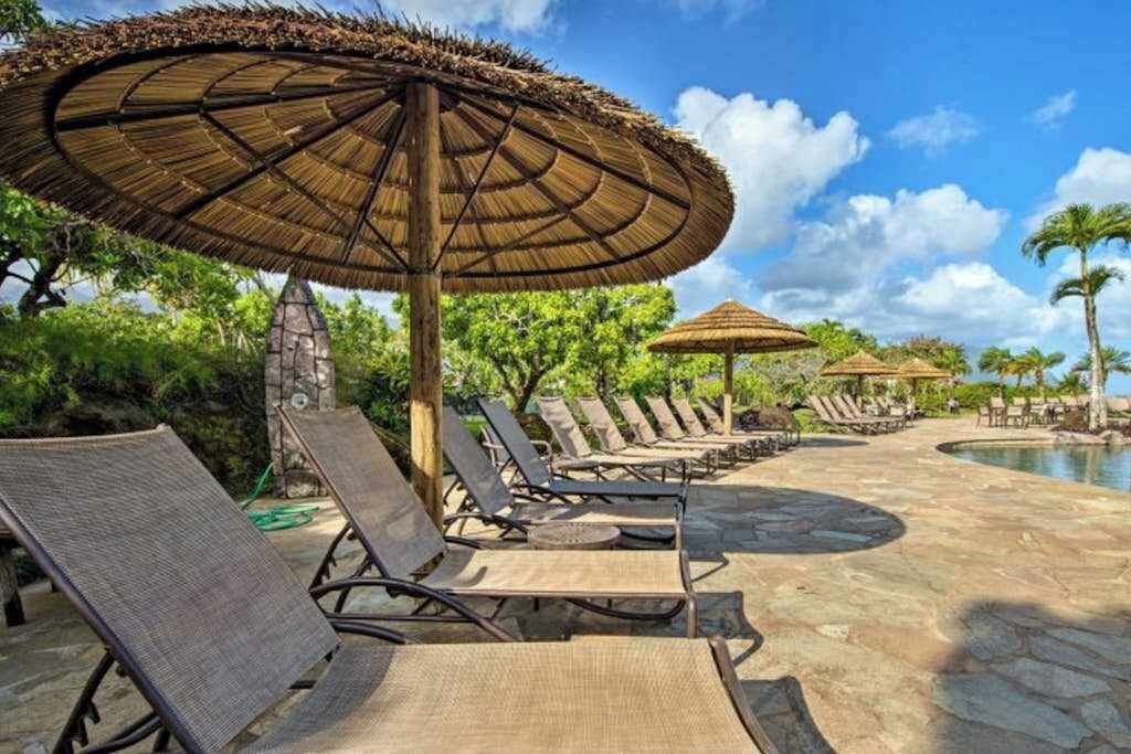 A poolside area with lounge chairs and thatched umbrellas.