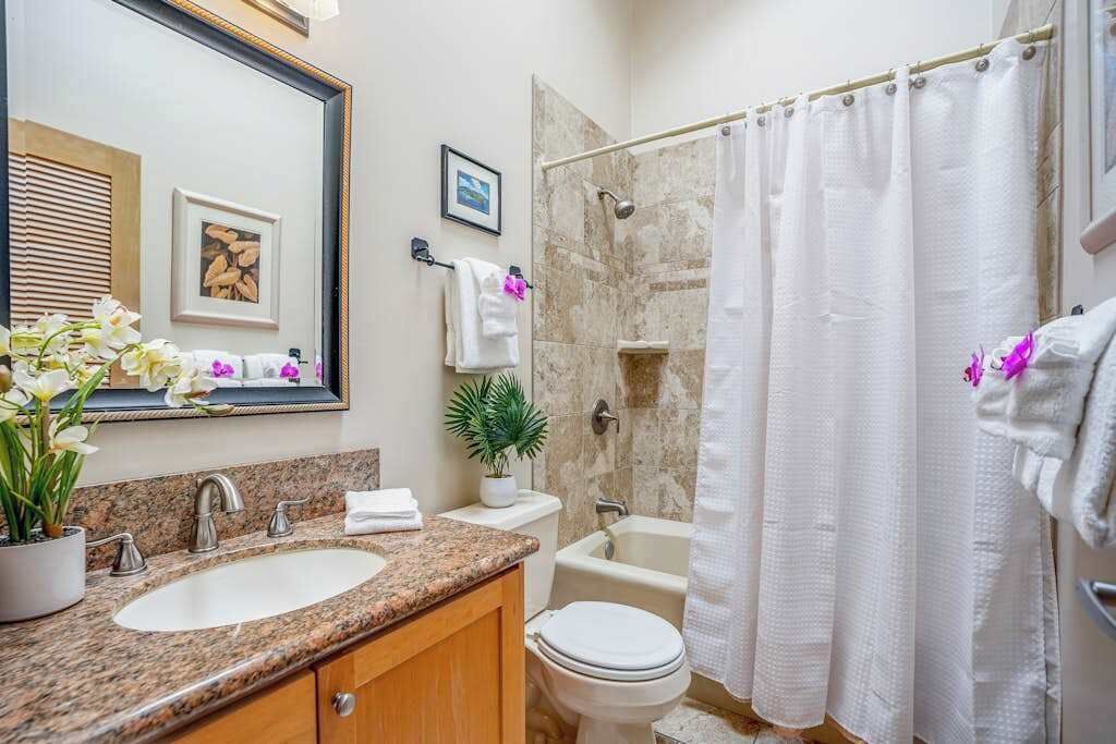 Une salle de bain équipée d’un lavabo, de toilettes, d’une douche et d’un grand miroir.