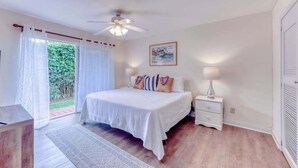 Un dormitorio con cama, mesita de noche y ventilador de techo.