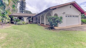 Una casa de un piso con garaje, un porche cubierto con arcos y un césped bien cuidado.