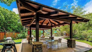 Eine Terrasse im Freien mit einer Holz-Pergola, Steinpfeilern und Sitzgelegenheiten.