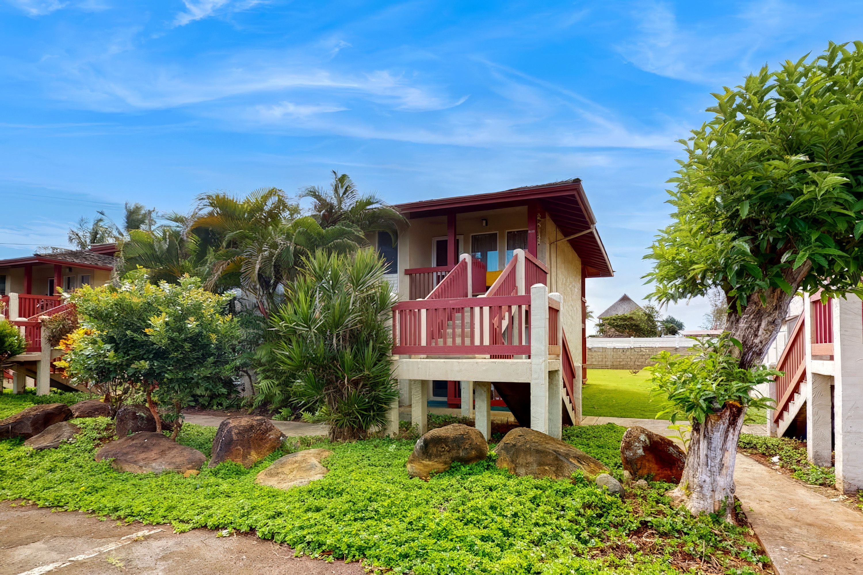 Ein hotelähnliches Bungalow mit Balkon, umgeben von üppiger Vegetation und Felsen.