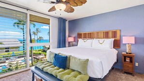 Una camera d'hotel con un letto, una panca, un comodino, una lampada e una ventola a soffitto.