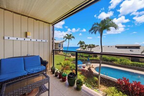 Ein Balkon mit Blick auf einen Swimmingpool, einer Couch und Topfpflanzen.