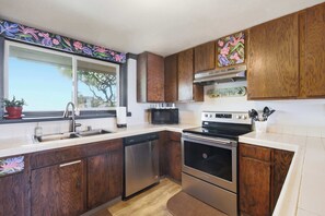 Eine Küche mit Holzschränken, einem Edelstahl-Geschirrspüler, einer Mikrowelle und einem Backofen.