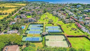 Oversigtsbillede af et boligområde med flere tennisbaner, huse og en kystlinje.