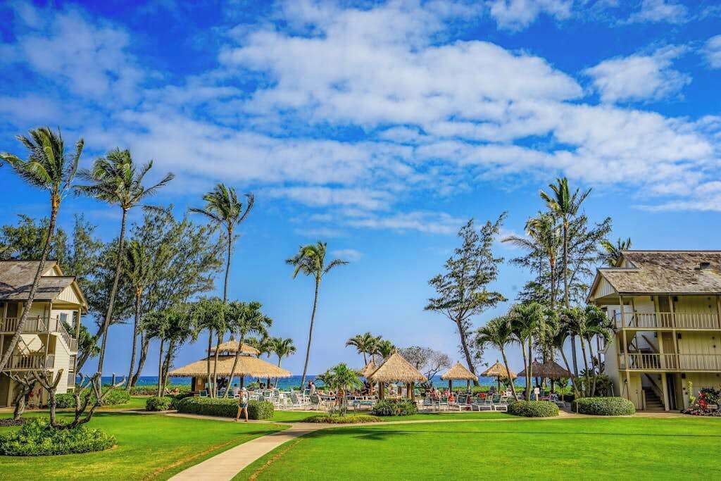 A resort with a pool, palm trees, and a clear sky.