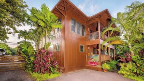 A two-story wooden building with a balcony, surrounded by tropical plants. - NEW Fall $ale Walk to Hanalei Bay from a Waterfall View Home TVNC#5120 (Hanalei)