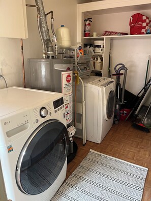 Une buanderie équipée d’un lave-linge et d’un sèche-linge à chargement frontal, d’un chauffe-eau et d’un extincteur.