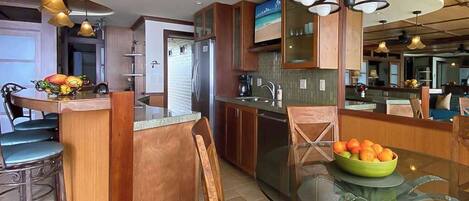 A modern kitchen with wooden cabinets, a glass island, and pendant lighting.