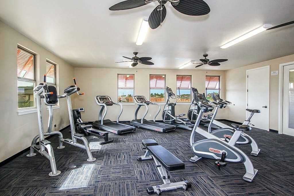 A gym with treadmills, elliptical machines, and a bench.
