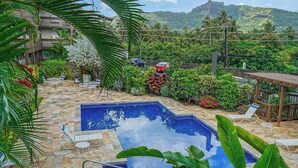 Una piscina amb gandules, envoltada de plantes tropicals i vistes a les muntanyes.