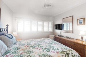 A bedroom with a bed, dresser, TV, and window blinds. - NEW Coconut Coast Oceanfront Stay Near Kapa'a (Kapaa)