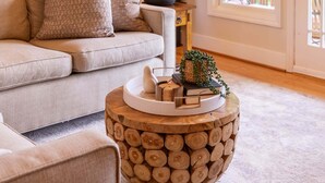 A living room with a sofa, a round wooden coffee table, a lamp, and a fireplace. - Mount LiveJoy- two king suites, community amenities! (Boone)