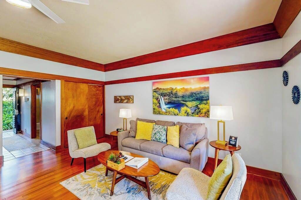A living room with a sofa, armchairs, a coffee table, and a painting on the wall.