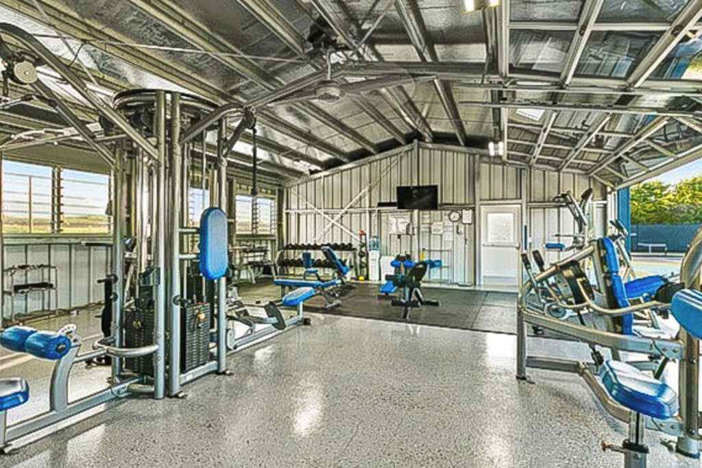 A gym with various exercise equipment, a large mirror, and a television screen.