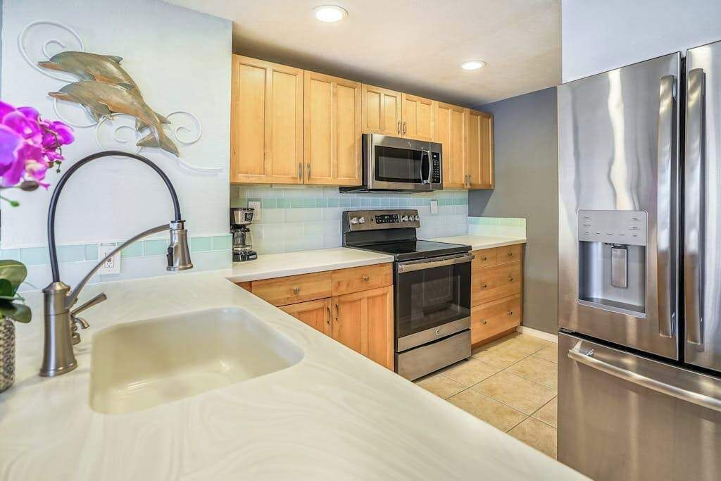 A kitchen with wooden cabinets, stainless steel appliances, a microwave, oven, and a refrigerator.
