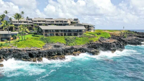 A coastal hotel with multiple buildings, a rocky shoreline, and waves crashing against the rocks. - New Fall Sale Breezy Two-Story Poipu Escape with Pool and Hot Tub (Koloa)