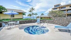 A pool area with lounge chairs and umbrellas, a stone wall, and a view of the ocean. - New Fall Sale Breezy Two-Story Poipu Escape with Pool and Hot Tub (Koloa)