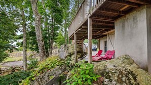 Ett takförsett utomhusområde med sittplatser och röda stolar, omgivet av en naturlig landskap och träd.