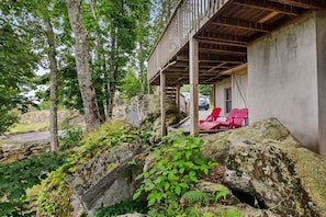 A covered outdoor seating area with red chairs, surrounded by natural landscape and trees. - Beech on The Rocks | pet friendly, club access, mtn views (Banner Elk)