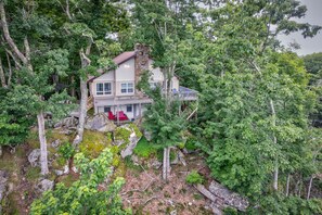 A two-story house with a stone facade, surrounded by dense forest. - Beech on The Rocks | pet friendly, club access, mtn views (Banner Elk)