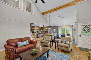 A spacious living area with a leather sofa, two armchairs, a coffee table, and a kitchen in the background. - Beech on The Rocks | pet friendly, club access, mtn views (Banner Elk)
