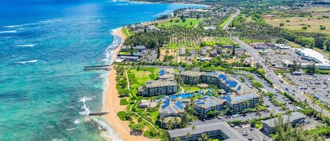 Un complejo turístico frente al mar con propiedades en la playa, paneles solares y vistas despejadas del océano.
