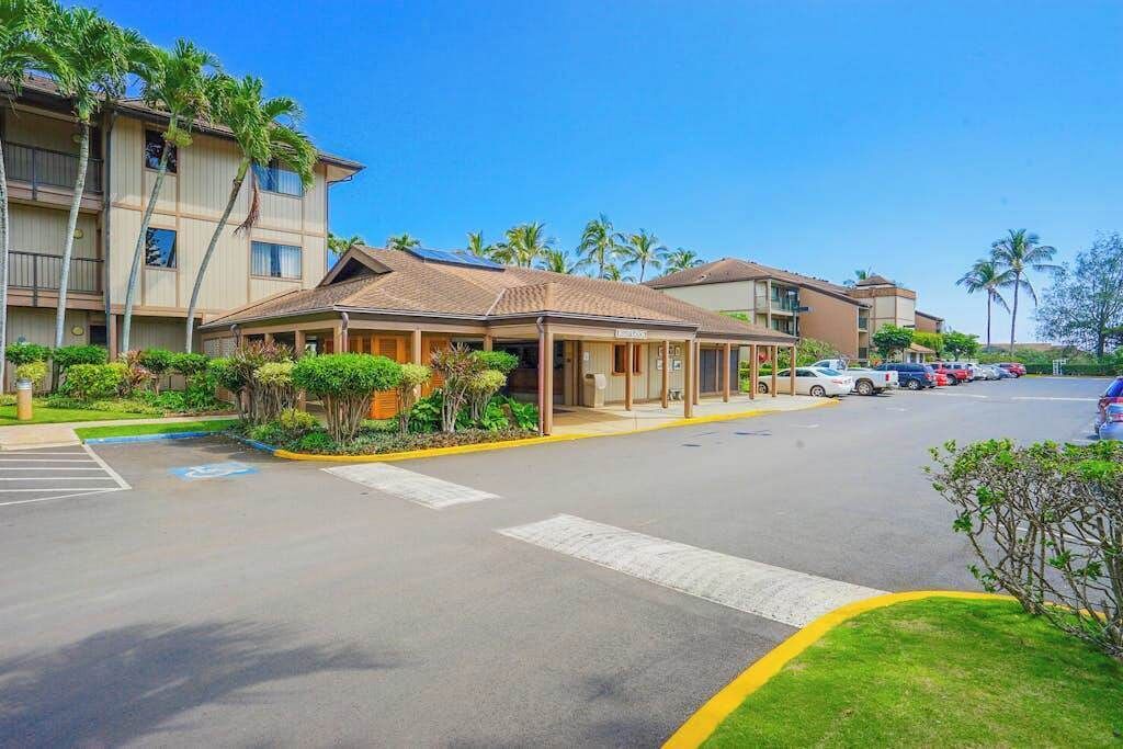 A hotel with a covered entrance, a parking lot, and a building with a flat roof.