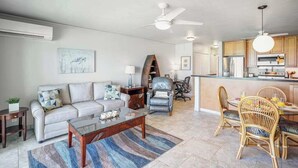 A modern living room with a sofa, coffee table, and dining area with chairs. - *NEW* Oceanfront Kapaa Retreat with Private Lanai and Pool (Kapaa)