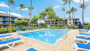 A swimming pool with blue lounge chairs, palm trees, and hotel buildings in the background. - *NEW* Oceanfront Kapaa Retreat with Private Lanai and Pool (Kapaa)