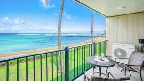 A balcony with a view of the ocean, a table with chairs, and an air conditioning unit. - *NEW* Oceanfront Kapaa Retreat with Private Lanai and Pool (Kapaa)