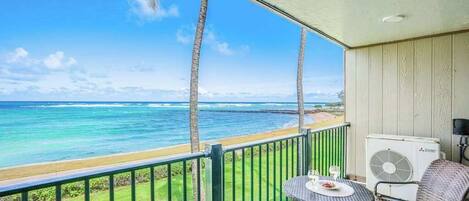 A balcony with a view of the ocean, a table with chairs, and an air conditioning unit.