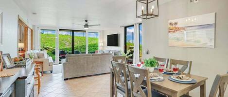 A spacious living area with a dining table, sofas, and a kitchen area.