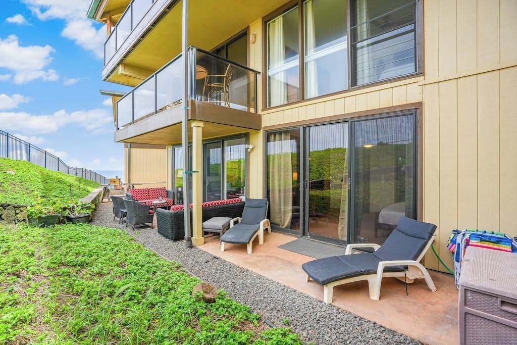 A two-story building with a balcony, outdoor seating area, and a view of the landscape.