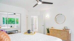 Ein Schlafzimmer mit Bett, Kommode, Spiegel und Deckenventilator.