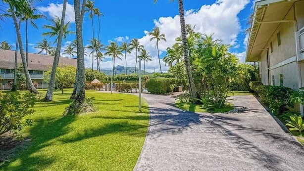 A pathway leading to a building with a thatched roof, surrounded by palm trees and a clear blue sky. - New Fall Special Kapaa 1BR with 3 Pools, 2 Hot Tubs and Beach Path (Kapaa)