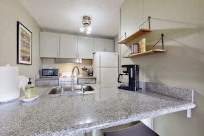 A kitchen with granite countertops, a sink, a microwave, a refrigerator, and a coffee maker. - New Fall Special Kapaa 1BR with 3 Pools, 2 Hot Tubs and Beach Path (Kapaa)