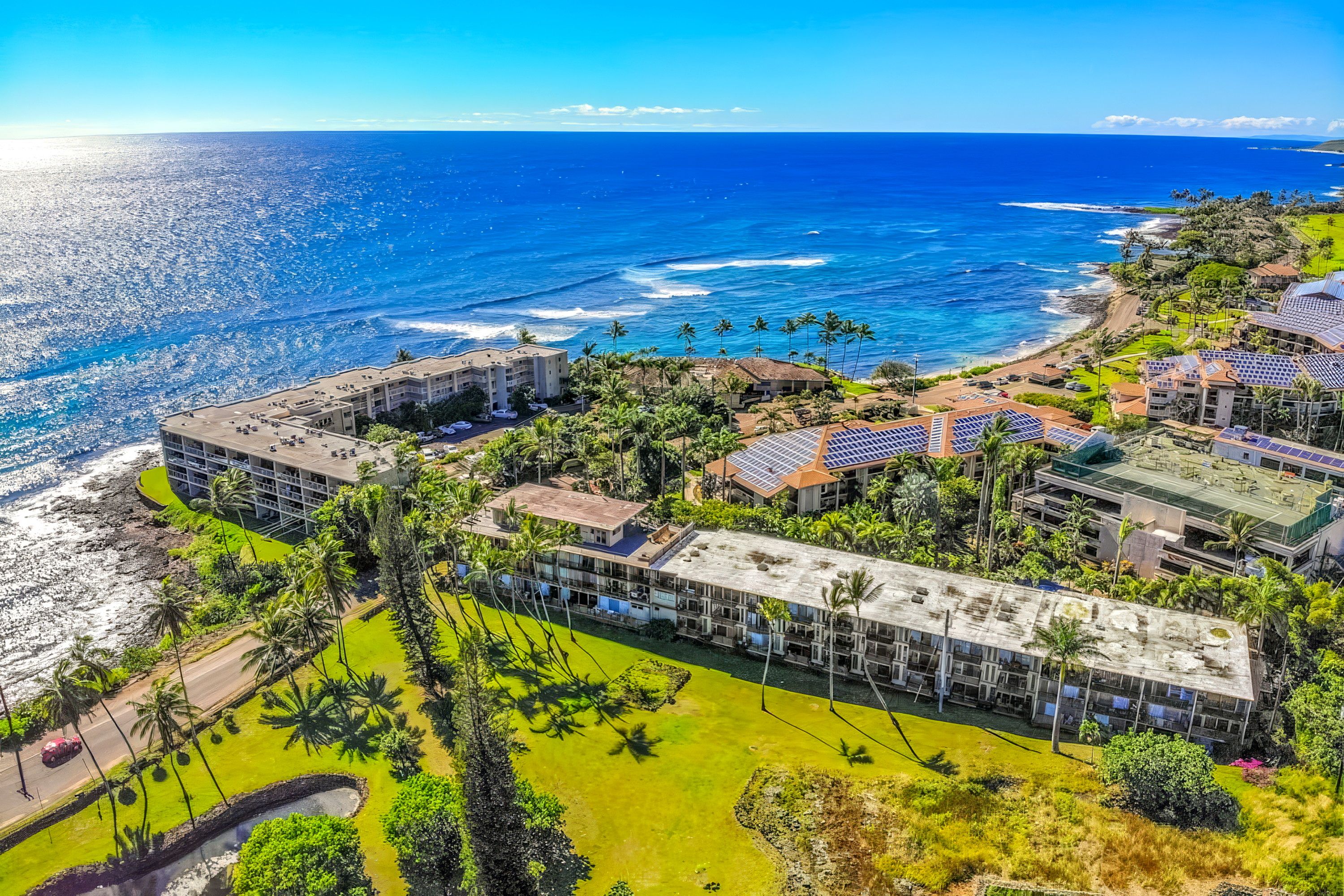 Ein Küstenresort mit mehreren Gebäuden, einer Strandpromenade und Solaranlagen auf den Dächern.