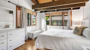 Une chambre à coucher avec un lit, une commode, un banc et de grandes fenêtres.