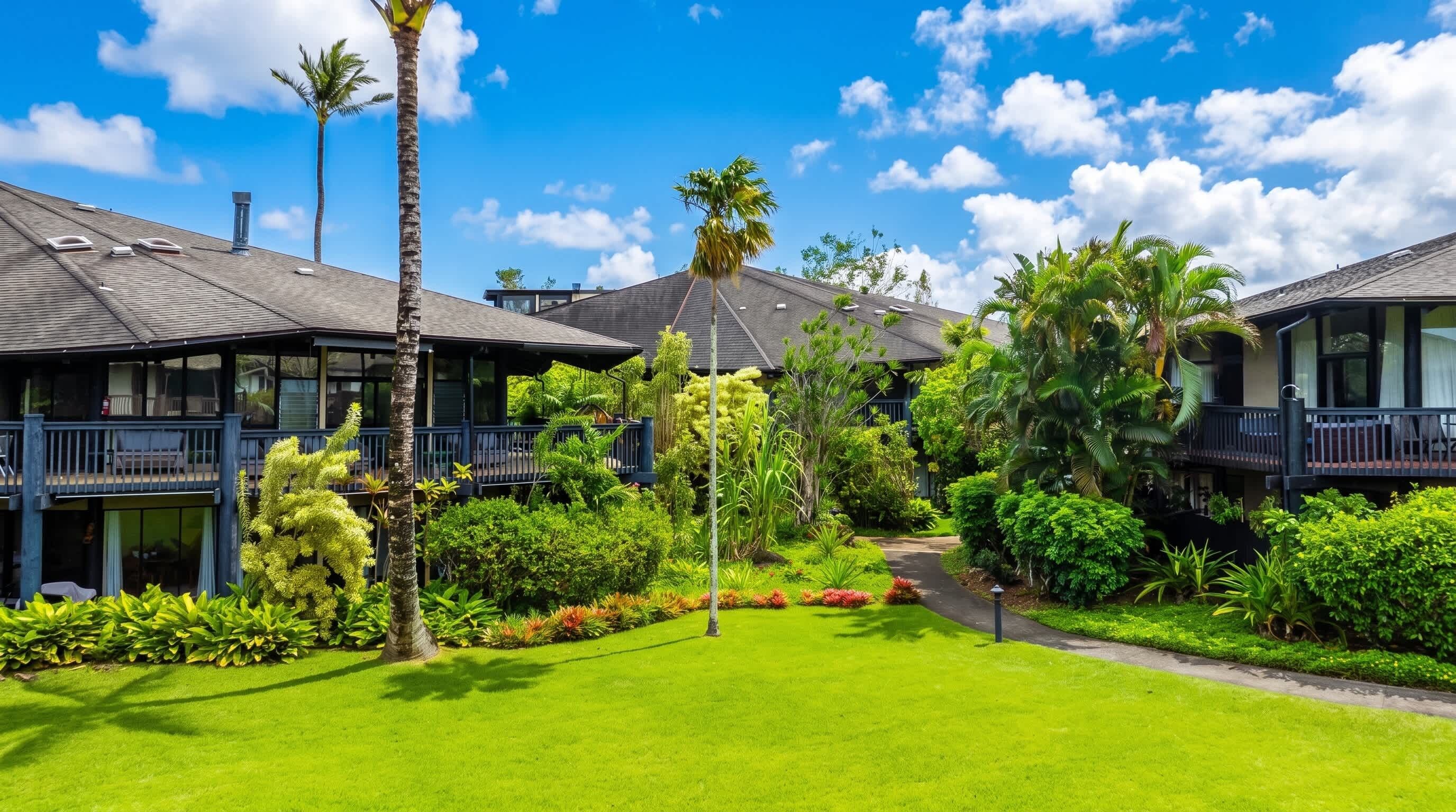 Um hotel com edifícios de vários andares, um jardim bem cuidado com diversas plantas e um céu azul límpido.