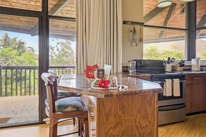 Une cuisine avec un îlot central en bois, une cuisinière et une vue sur l’extérieur.
