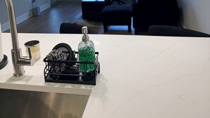 Moderni keittiö, jossa on työtaso, pesuallas ja kaksi riippuvalaisinta.