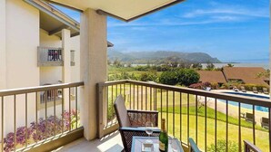 Un balcon avec une table, une chaise et une bouteille de champagne.