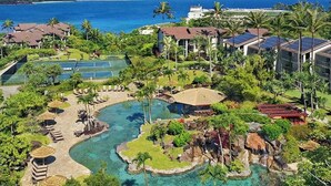 Un complexe hôtelier doté d’une piscine, de palmiers et offrant une vue sur l’océan.
